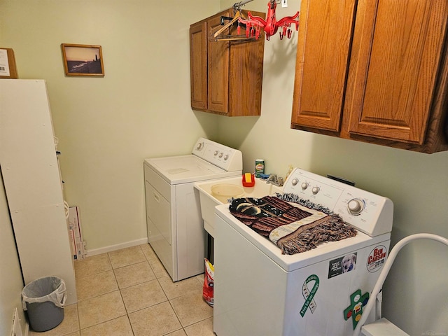 washroom with light tile patterned floors, washing machine and clothes dryer, and cabinets