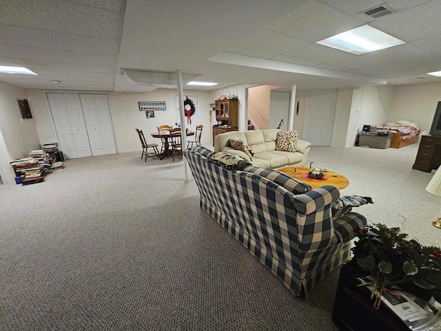 living room featuring a drop ceiling and carpet floors