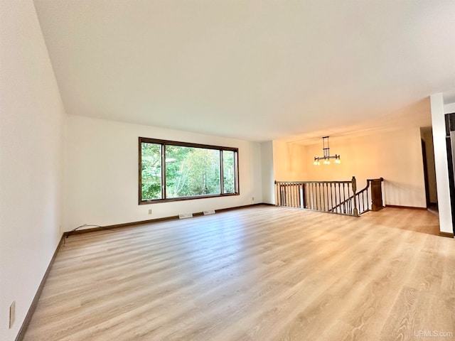 empty room featuring light hardwood / wood-style floors and a chandelier