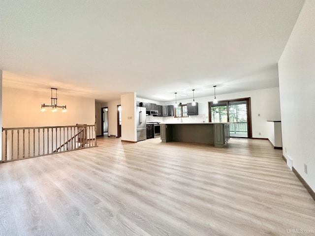 kitchen with appliances with stainless steel finishes, a kitchen island, an inviting chandelier, and decorative light fixtures