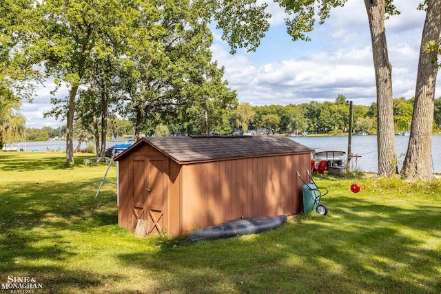 view of outdoor structure featuring a water view and a yard