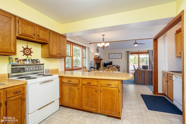 kitchen with ceiling fan with notable chandelier, white appliances, kitchen peninsula, and hanging light fixtures