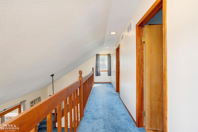 corridor with light carpet, vaulted ceiling, and a textured ceiling