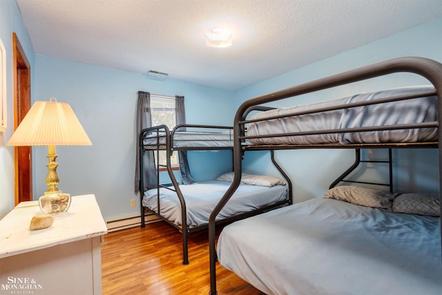 bedroom featuring a textured ceiling and light hardwood / wood-style flooring