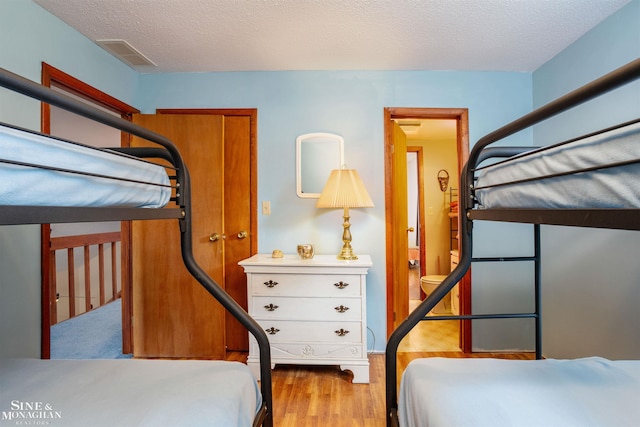 bedroom with a textured ceiling and light hardwood / wood-style floors