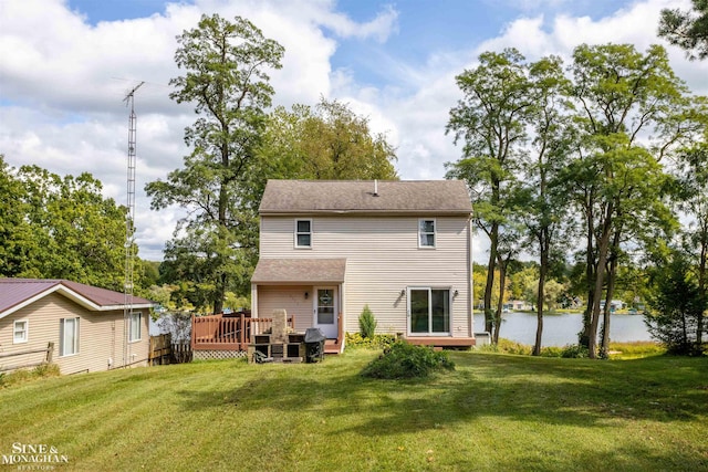 rear view of property with a yard and a deck with water view