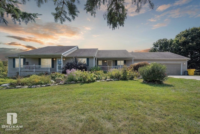 ranch-style home featuring a garage, a yard, and covered porch