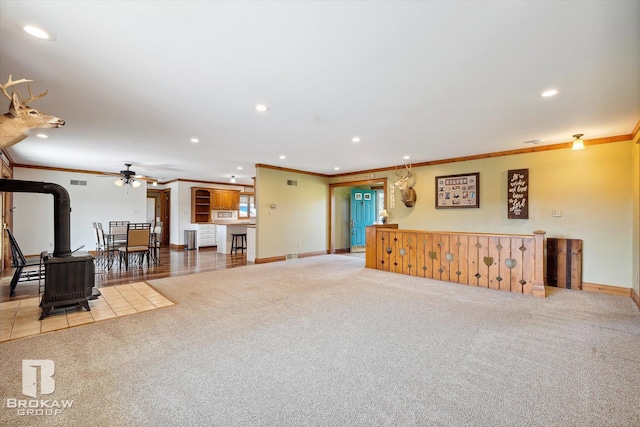 living room with a wood stove, crown molding, and carpet floors