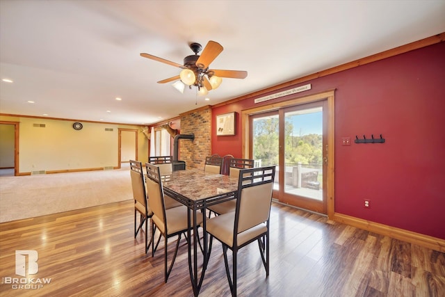 dining room with a wood stove, crown molding, ceiling fan, and hardwood / wood-style floors