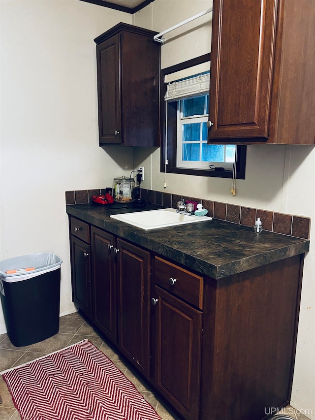 kitchen with light tile patterned floors, dark brown cabinets, and sink