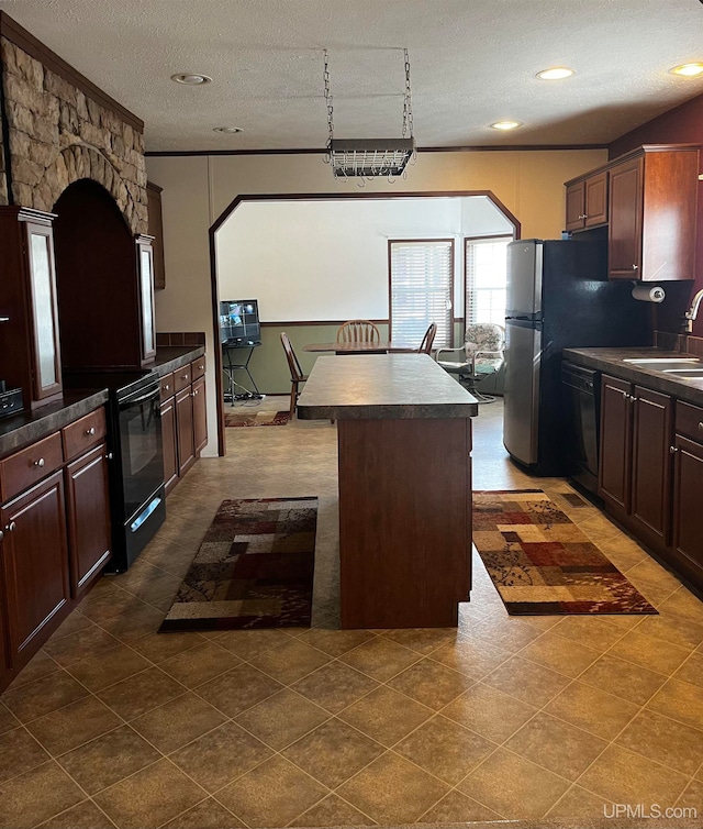 kitchen with dark tile patterned floors, sink, black appliances, a kitchen island, and a textured ceiling