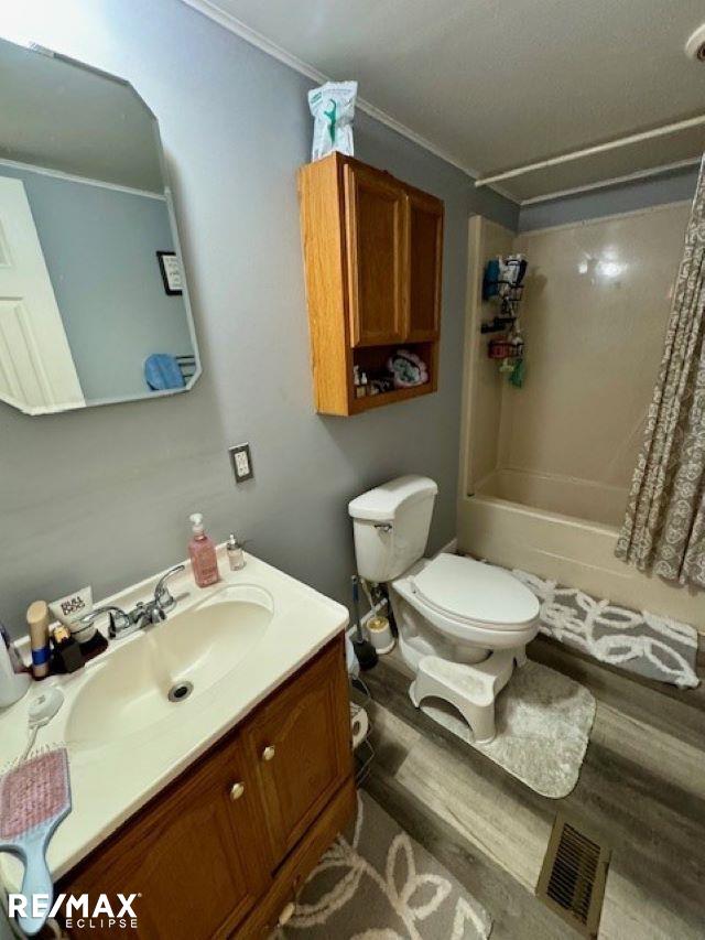 full bathroom featuring vanity, crown molding, toilet, hardwood / wood-style flooring, and shower / bath combo