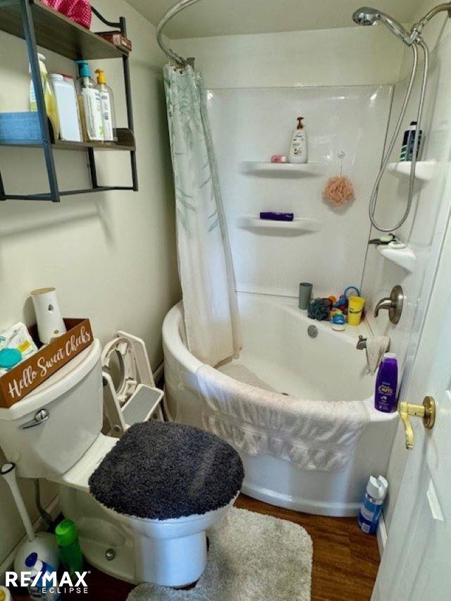 bathroom featuring shower / bath combo with shower curtain, toilet, and hardwood / wood-style floors