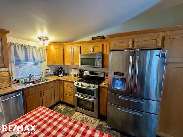 kitchen with vaulted ceiling, stainless steel appliances, and sink