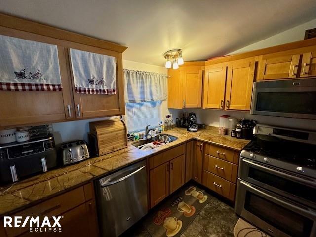 kitchen with lofted ceiling, stainless steel appliances, and sink