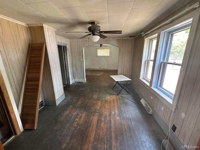 empty room featuring dark hardwood / wood-style floors, ceiling fan, and wood walls