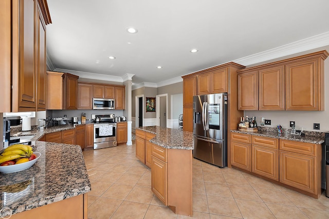 kitchen featuring ornamental molding, light tile patterned floors, a kitchen island, stainless steel appliances, and dark stone countertops