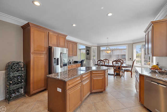 kitchen with dark stone counters, ornamental molding, appliances with stainless steel finishes, and a kitchen island