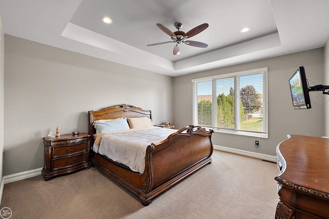 carpeted bedroom featuring ceiling fan and a raised ceiling