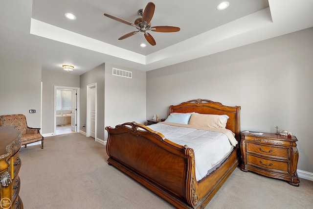 bedroom featuring light carpet, connected bathroom, ceiling fan, and a raised ceiling