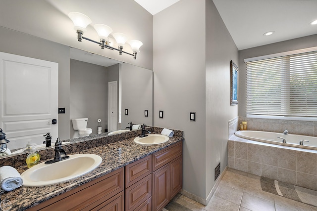 bathroom featuring vanity, tile patterned flooring, a relaxing tiled tub, and toilet