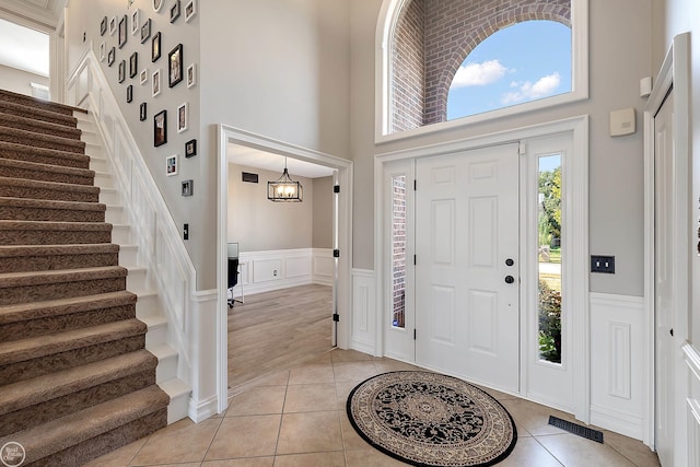 tiled entrance foyer featuring a towering ceiling and a chandelier