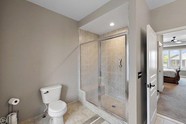 bathroom with tile patterned flooring, ceiling fan, a shower with shower door, and toilet