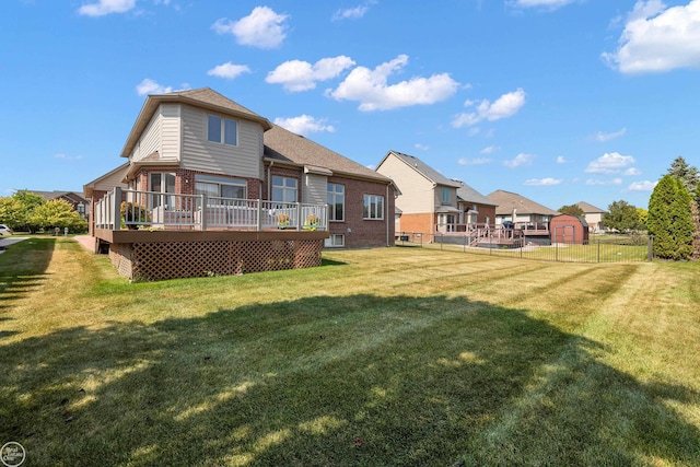 rear view of house featuring a lawn, a deck, and a storage unit