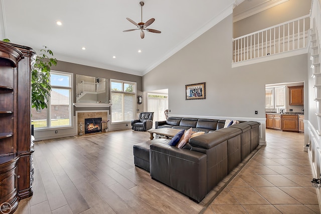 living room featuring ceiling fan, light hardwood / wood-style flooring, ornamental molding, and high vaulted ceiling