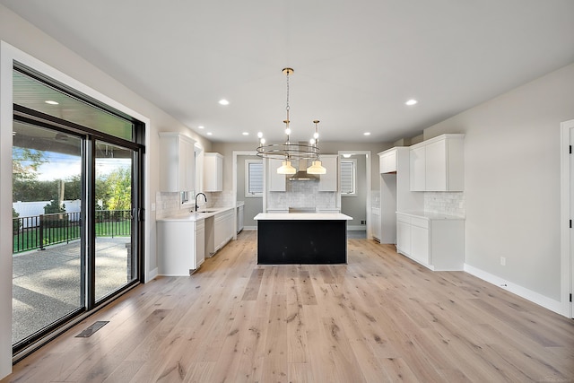 kitchen featuring an inviting chandelier, hanging light fixtures, a center island, and white cabinets