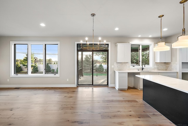 kitchen featuring white cabinets, decorative light fixtures, and a healthy amount of sunlight