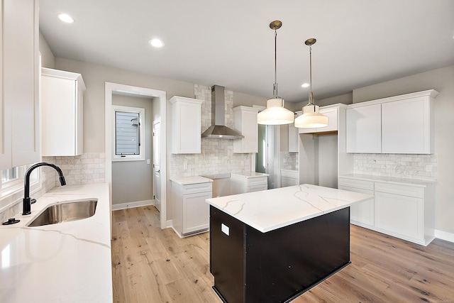 kitchen with white cabinets, wall chimney exhaust hood, sink, and a kitchen island