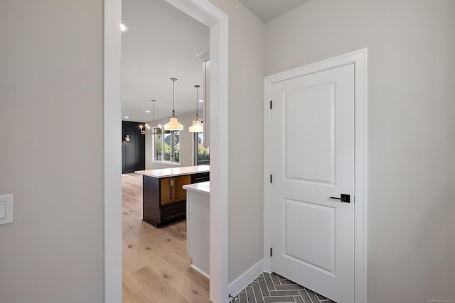 hall featuring light wood-type flooring and a chandelier