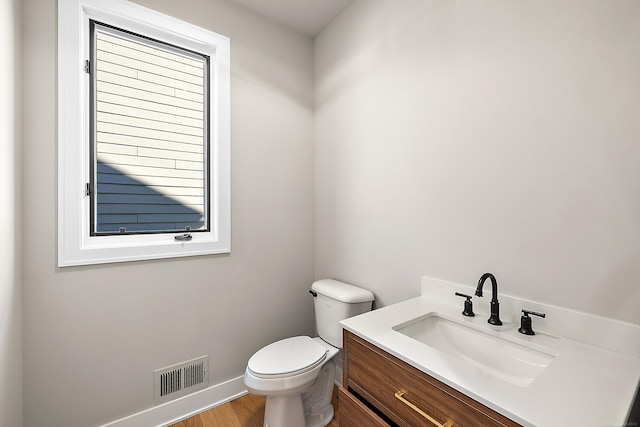 bathroom featuring a healthy amount of sunlight, vanity, toilet, and wood-type flooring