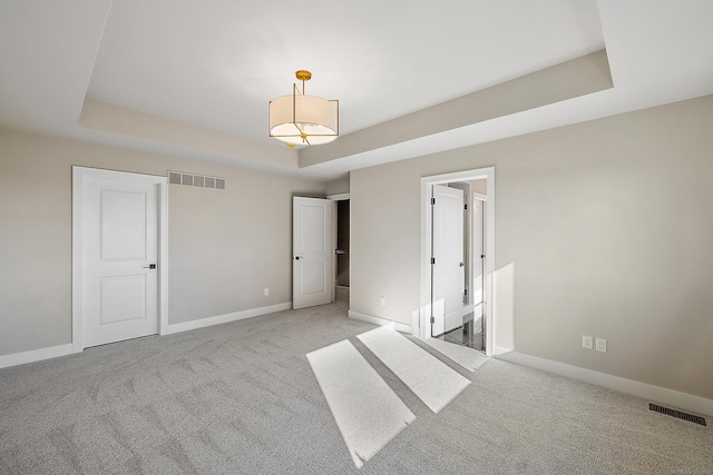 empty room with light carpet and a tray ceiling