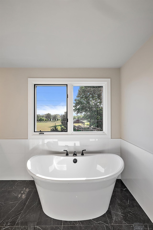 bathroom with tile walls and a tub