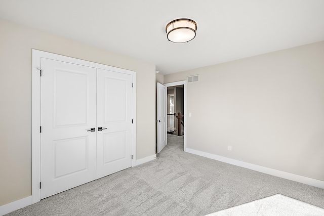 unfurnished bedroom featuring light colored carpet and a closet