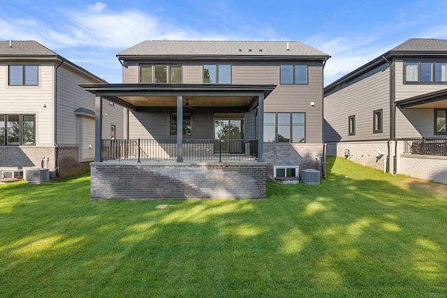 rear view of property with ceiling fan, a lawn, and central AC