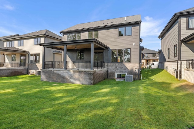 rear view of property featuring a lawn, ceiling fan, and central air condition unit