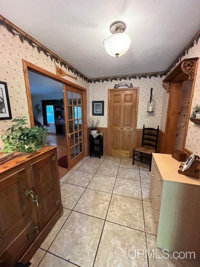 interior space featuring french doors, a textured ceiling, and light tile patterned floors