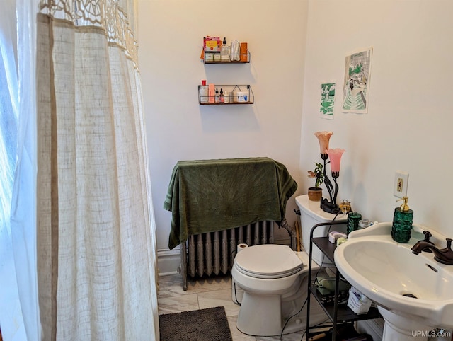 bathroom with radiator, sink, toilet, and a shower with shower curtain