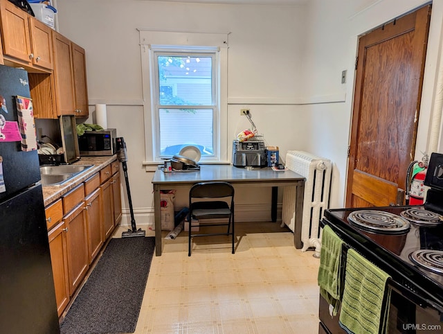 kitchen with radiator, electric stove, black refrigerator, and sink