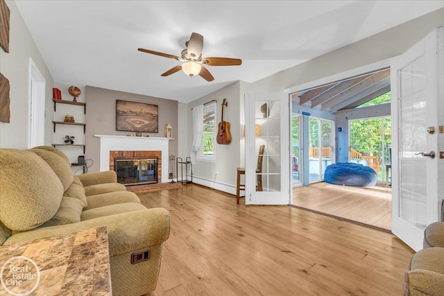 living room featuring light wood-type flooring, plenty of natural light, ceiling fan, and a brick fireplace