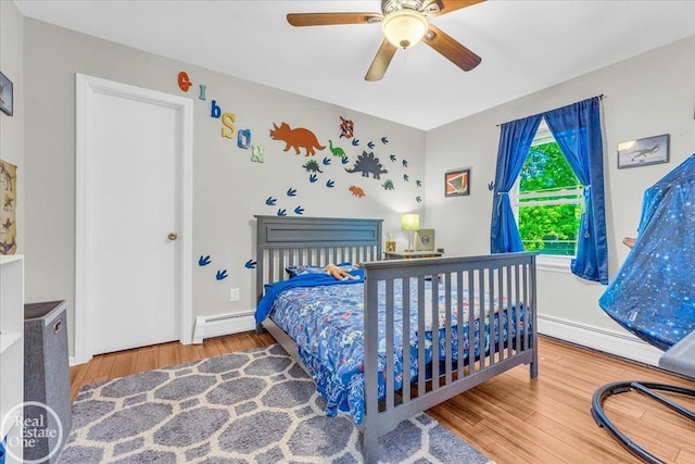 bedroom with ceiling fan, baseboard heating, and hardwood / wood-style flooring