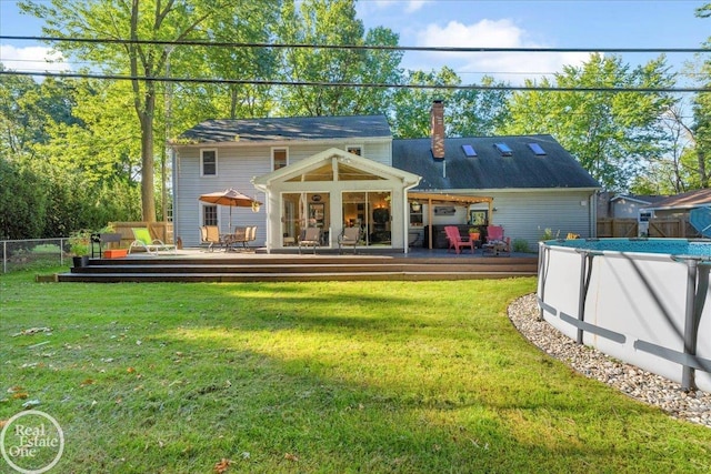 rear view of house featuring a yard and a swimming pool side deck