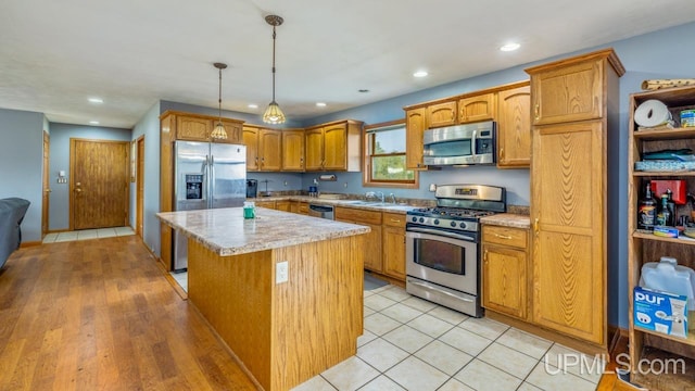 kitchen with hanging light fixtures, light hardwood / wood-style floors, light stone countertops, stainless steel appliances, and a center island