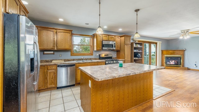 kitchen with appliances with stainless steel finishes, light hardwood / wood-style floors, a center island, ceiling fan, and decorative light fixtures