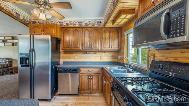 kitchen with ceiling fan, sink, appliances with stainless steel finishes, light wood-type flooring, and crown molding