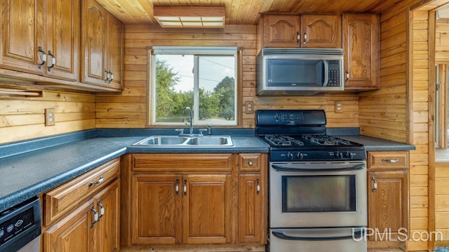 kitchen featuring stainless steel appliances, wood walls, wooden ceiling, and sink