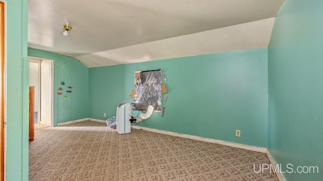 carpeted empty room with vaulted ceiling and baseboards